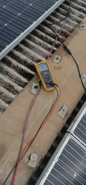 Multimeter testing the output of rooftop solar panels
