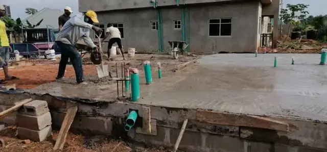 Workers casting a ground slab around plumbing sleeves