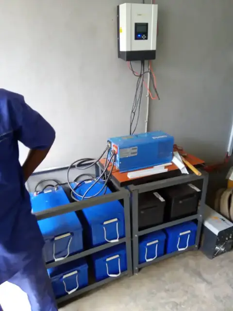 Inverter mounted on a wall above a rack of batteries